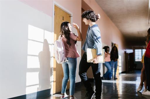 Dos alumnos se saludan en pasillo de centro educativo