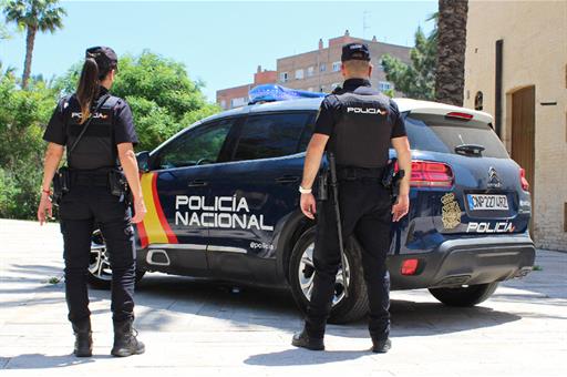 Dos policías nacionales junto a su coche patrulla