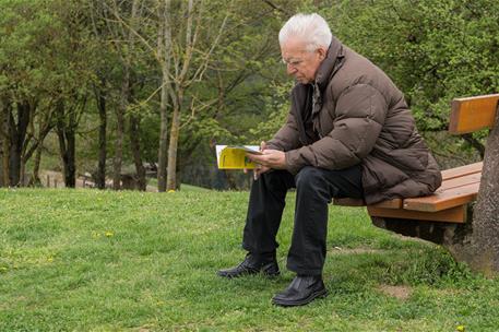 Persona mayor sentao leyendo en un parque
