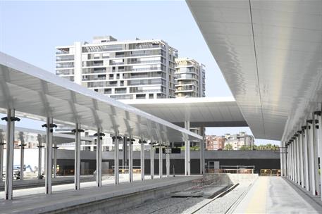 Andenes ferroviarios casi terminados con marquesinas metálicas blancas y vías en proceso de instalación.